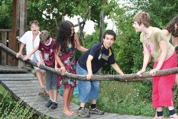 Gruppe von Jugendlichen, die über eine Hängebrücke balancieren