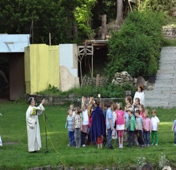 Ökumenischer Gottesdienst Naturbühne Kinder mit ihren Familien feiern auf einer Wiese vor einer Naturbühne einen Freiluftgottesdienst