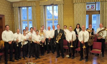 Ökumenische Blasmusik für den lieben Gott Eine einheitlich gekleidete Posaunenchorgruppe steht mit Instrumenten in den Händen im Historischen Ratssaal Speyer